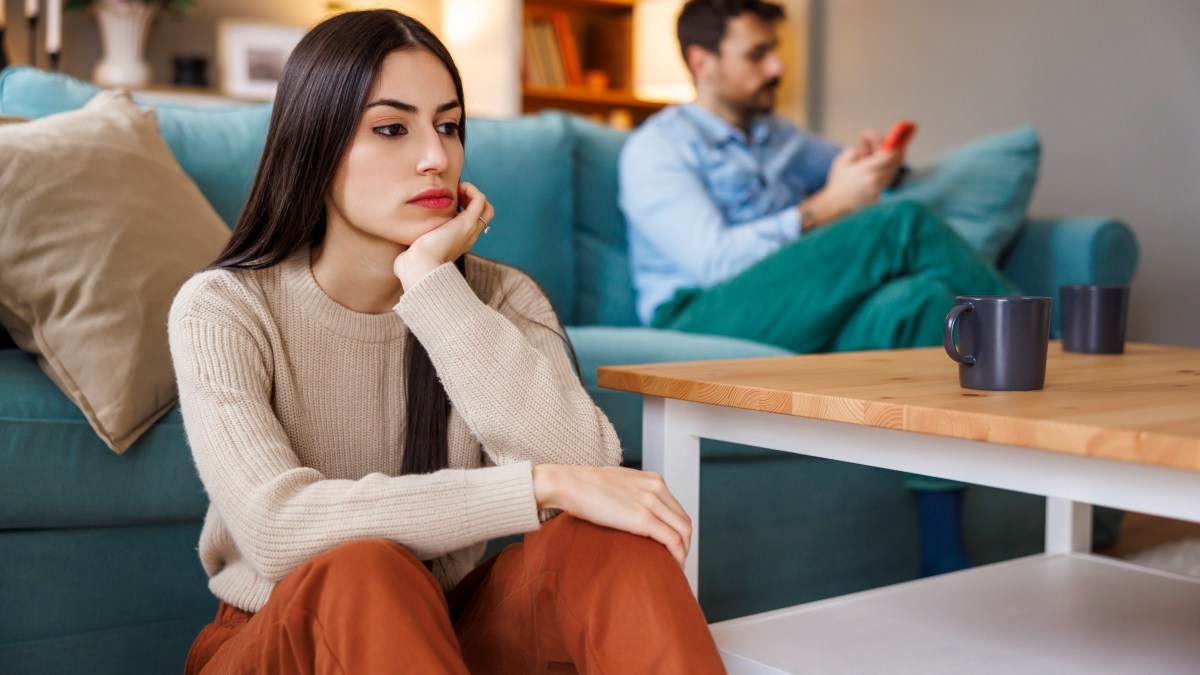 Young couple unhappy and angry after arguing at home, woman sitting sad and pensive while man using smart phone on the other side of the room | love,handsome,argument,couple,woman,young,boyfriend,caucasian,break up,displeased,pensive,husband,fighting,multi-ethnic,talking,two,spouse,domestic,beautiful,diversity,scrolling,problem,separation,marriage,sad,divorce,man,silence,relationship,together,stress,break,wife,smart phone,angry,people,home,lifestyle,anxiety,girlfriend,breakup,unhappy,brazilian,person,family,married - shutterstock_2522788305.jpeg