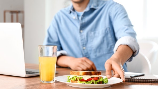 Young man with tasty sandwich in office