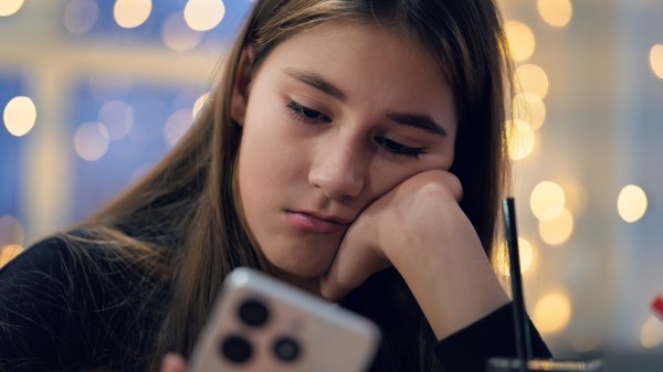 A teenage girl holds a smartphone in her hands